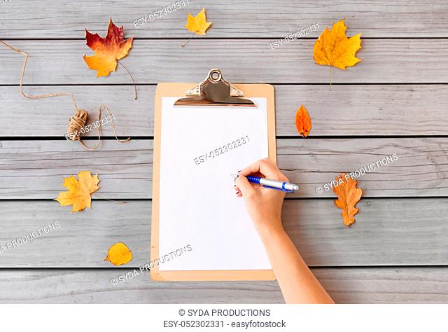 hand writing on white paper on clipboard in autumn