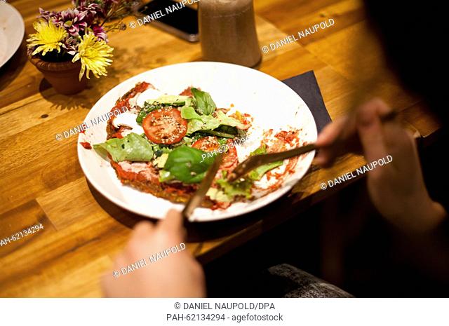 A guest eats a vegan pizza in the newly opened restaurant 'Rawtastic' in Berlin, 23 September 2015. The restaurant offers different raw dishes