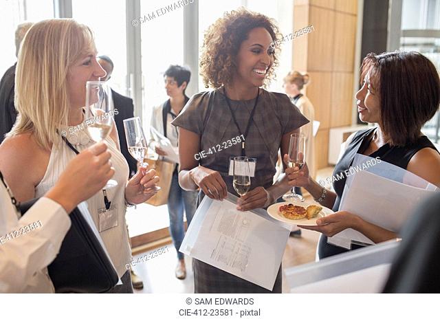 Businesswomen holding flutes of champagne and documents during meeting break
