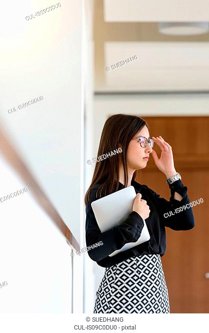 Businesswoman with digital tablet, daydreaming in office