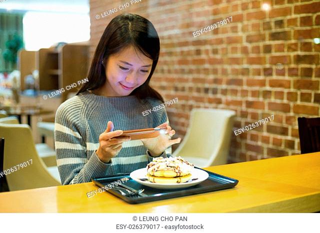 Woman taking photo on her pancake in coffee shop