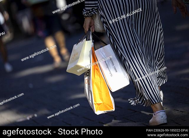 PRODUCTION - 24 June 2023, North Rhine-Westphalia, Cologne: A woman carries various paper bags in Cologne's Schildergasse. Photo: Thomas Banneyer/dpa
