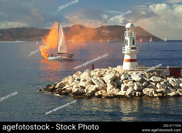 View to the people near the lighthouse taking photos of the parade of sailboats during the celebrations of the Independence day of Turkey at 29 October, Kas