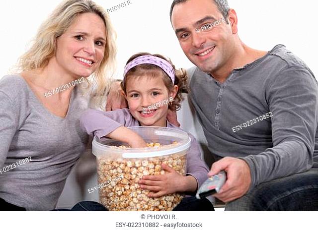 Family eating popcorn in front of television