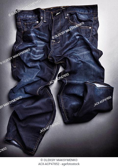 Photo of artistically crumpled blue stone washed mens jeans on gray background