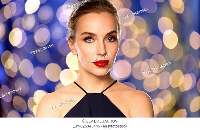 people, luxury and fashion concept - beautiful woman in black with red lips over blue holidays lights background