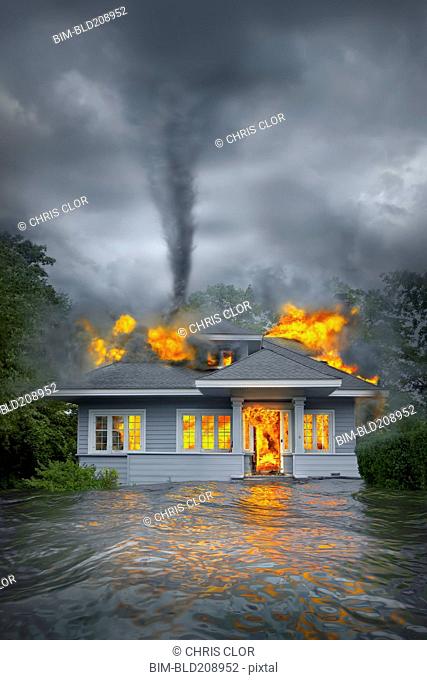 Burning house under tornado in flooded landscape