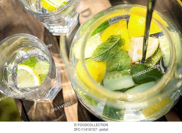 Lemon water with cucumber and mint on a wooden crate in the garden