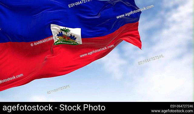 Haiti national flag waving in the wind on a clear day. Two horizontal bands of blue and red with national coat of arms in a small white rectangle in the center