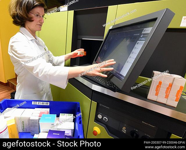 06 March 2020, Saxony, Leipzig: A pharmacist in the rose pharmacy in the Auwald forest uses a computer to fill the medicine store where a robot is working