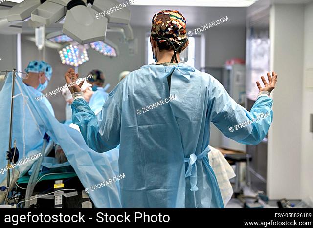 Surgeon stands in the operating room on the background of the surgery. He wears a colorful hat with medical clothes. Horizontal