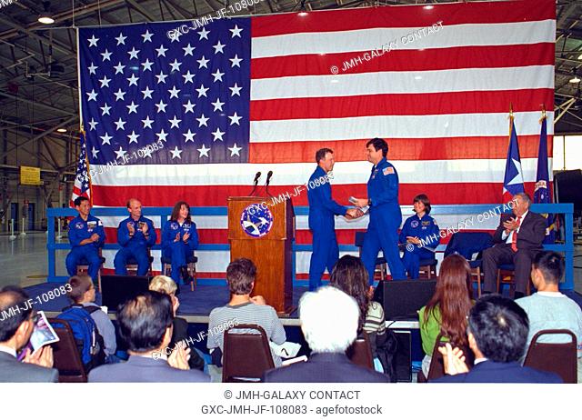 Astronauts Kevin R. Kregel (right center), mission commander, shakes hands with astronaut Dominic L. Gorie on a stage in Ellington Field's Hangar 990 during...