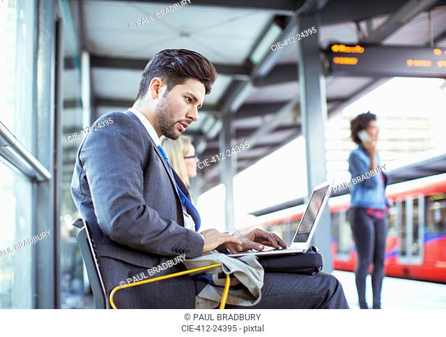 Businessman using laptop at train station
