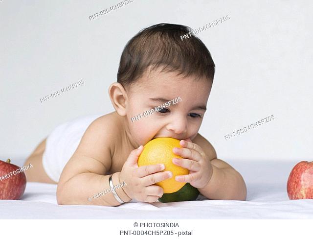 Close-up of a baby boy playing with an orange