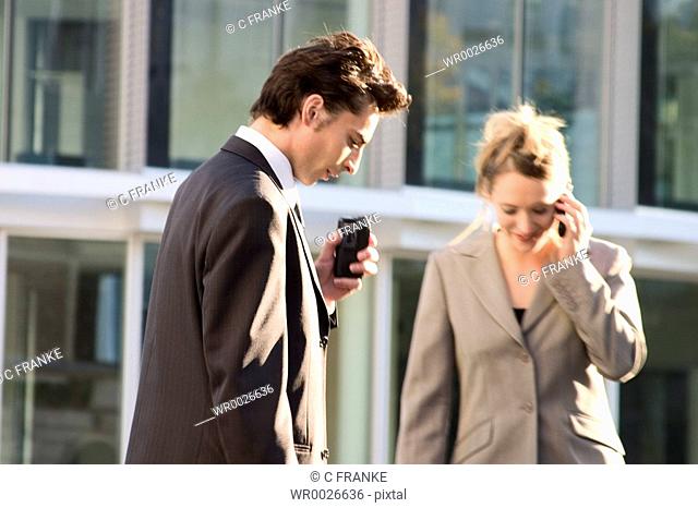 Businessman and businesswoman using mobile phones