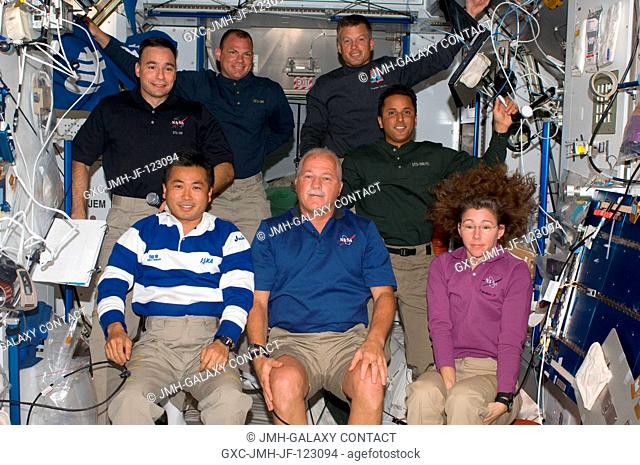 Seven of the ten crewmembers on the International Space Station are pictured in the Harmony node while Space Shuttle Discovery remains docked with the station