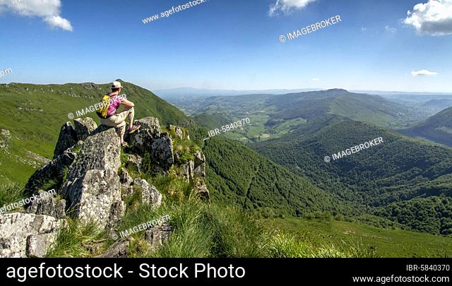 Hiker overlooking Cantal mountains, Auvergne Volcanoes Regional Natural Park, Cantal department, Auvergne-Rhone-Alpes, France, Europe