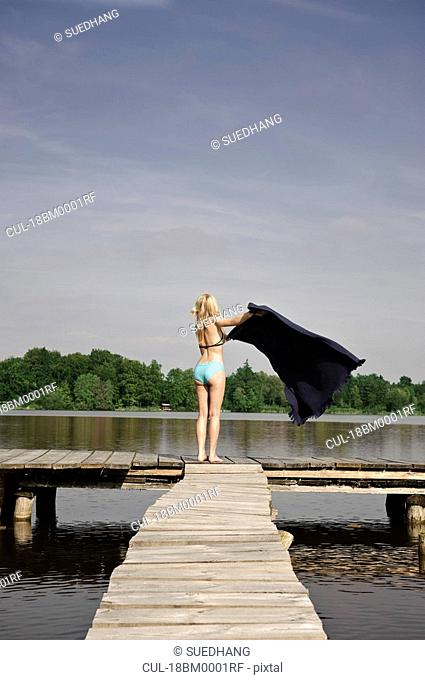 Woman spreading blanket on jetty