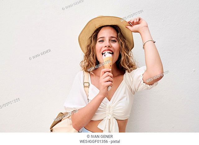 Portrait of happy young woman with hat eating ice cream