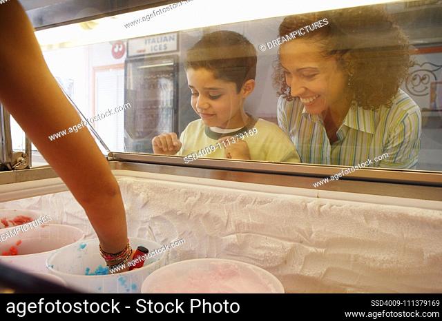 Mother and son watching through ice cream case window