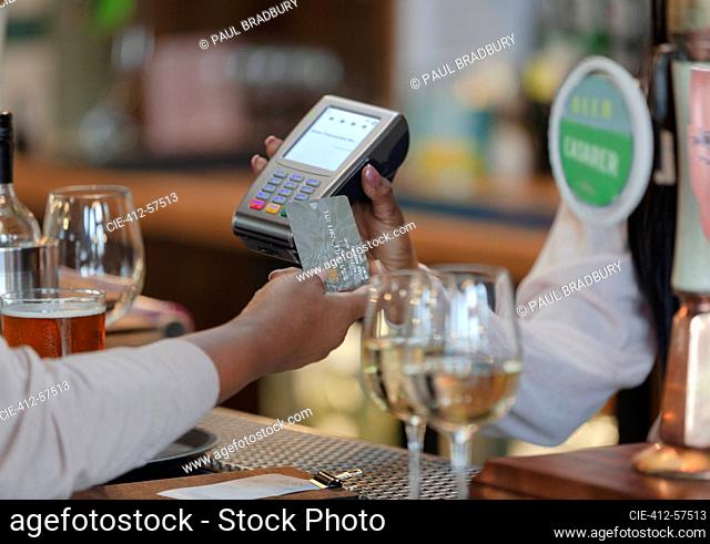 Close up customer paying bartender with smart card in bar