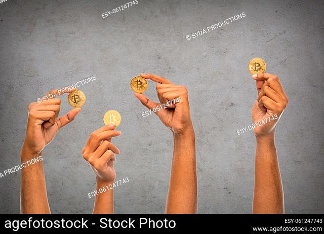 close up of hands with bitcoin over grey