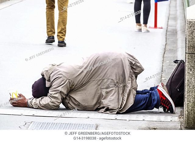 United Kingdom Great Britain England, London, Westminster Bridge, Thames River, Asian, man, prostrated on ground, holding McDonald's cup, begging, street beggar