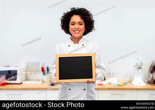 smiling female chef holding chalkboard on kitchen