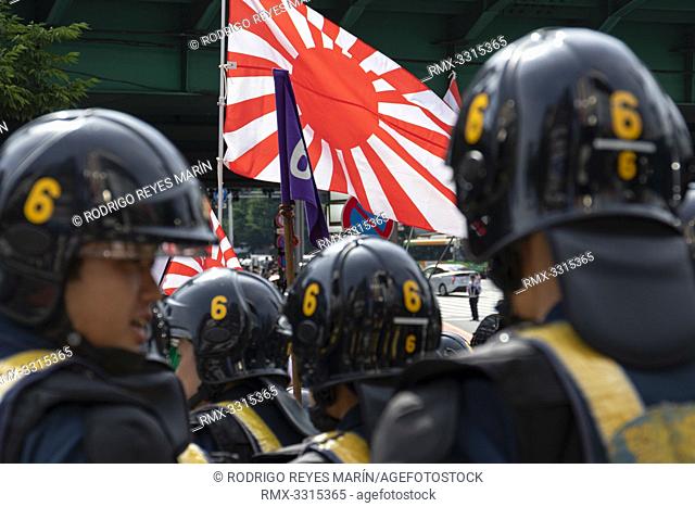 Tokyo Police officers prevent a clash between a small group of right-wing people holding the Rising Sun Flags and protesters holding placards against the US...