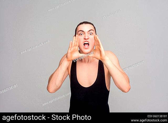 Anger man scream and shout at camera with big eyes. Studio shot, isolated on gray background