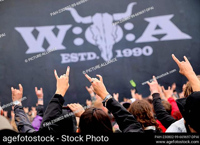 02 August 2023, Schleswig-Holstein, Wacken: Metal fans celebrate after the opening of the so-called ""infield"" in front of the ""Faster Stage""