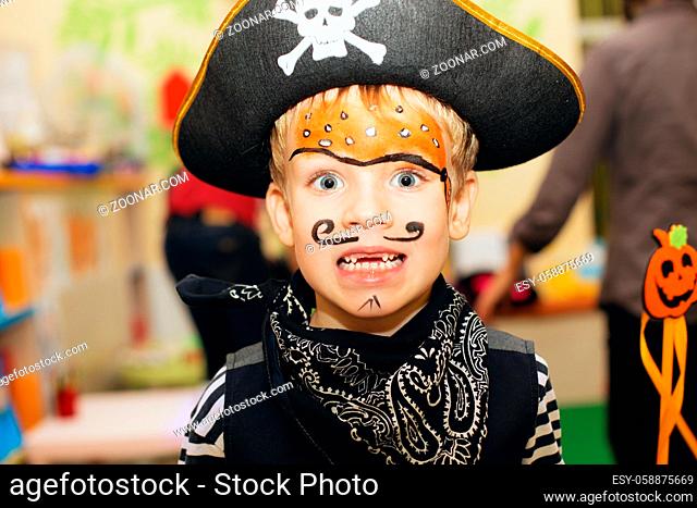 Halloween party. A little boy in a pirate costume and a makeup on his face is having a good time at the Halloween party. Face painting kids