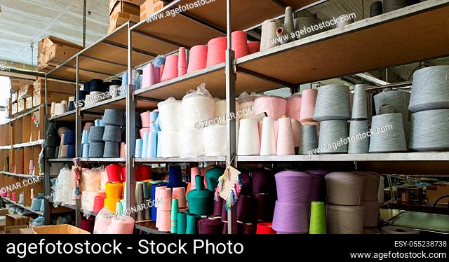 Color thread spools kept on shelves at knitting factory shot