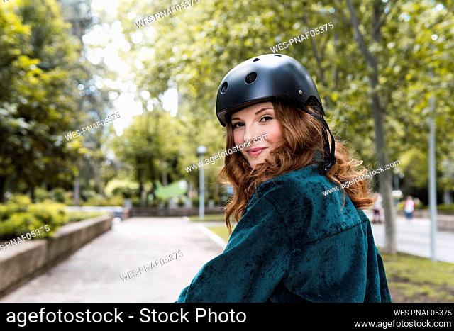 Smiling young woman wearing helmet in park