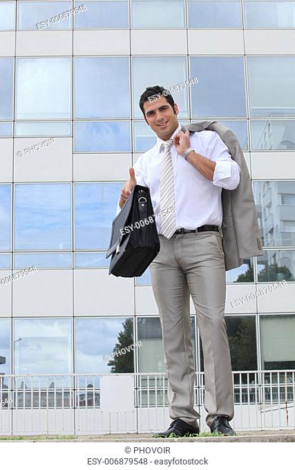 Businessman outside glass building holding satchel