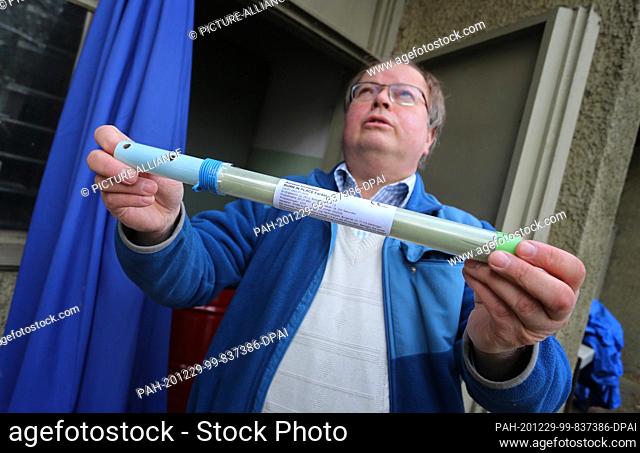 11 December 2020, Bavaria, Gersthofen: Peter Sauer holds a rocket for hail defense in his hands during production at his fireworks factory