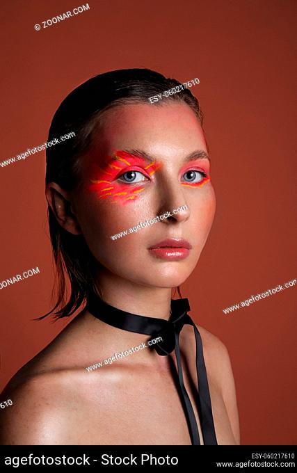 Vertical headshot of woman with bright eyeshadow make-up over red background. High quality photo