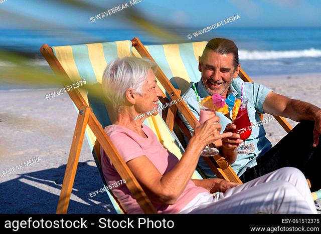 Senior Caucasian couple sitting on deck chairs at the beach