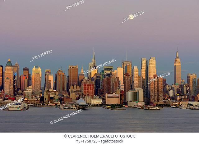 The waxing gibbous moon sits high in the magenta colored twilight sky over the New York City skyline the day before the full moon