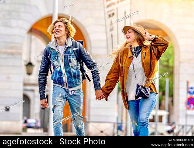 Carefree couple holding hands on vacation walking in city