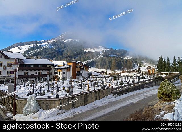 Cemetery in Kirchberg in Tyrol, Austria. Sunny winter morning, low clouds