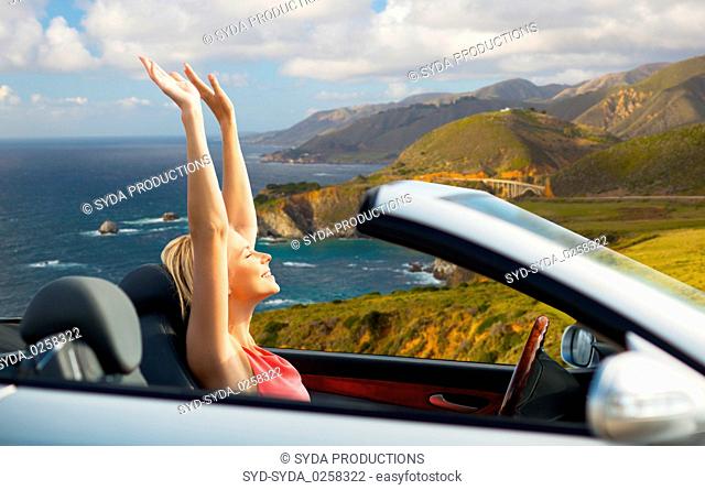 happy woman in convertible car on big sur coast