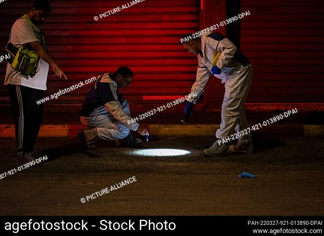 27 March 2022, Israel, Hadera: Members of the Zaka voluntary organization inspect the scene where two people were killed by gunmen in Hadera