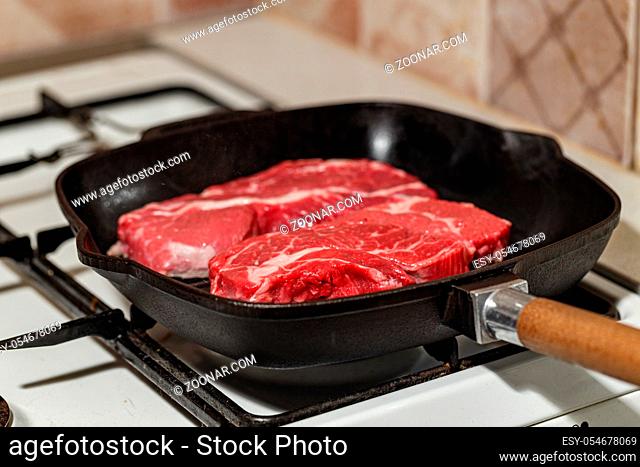 Two fresh raw meat of beef steak Prime Black Angus Chuck roll steak, grilled in pan on gas stove