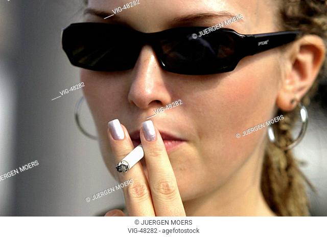 Young woman with sun glasses smoking a cigarette. - GERMANY, 10/08/2003
