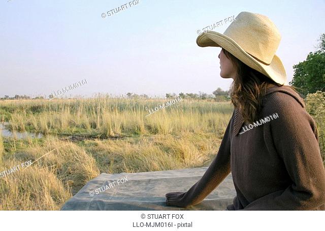 Profile view of a young woman sitting on a 4x4 on safari, Okavango Delta, Botswana