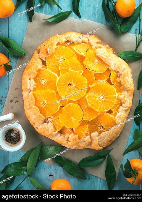 Top view of caraway and orange tart on baking paper over gray wooden table.Winter season and christmas ideas recipe-tart with caraway pastry and oranges