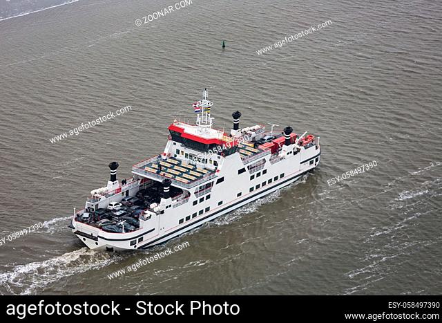 Dutch ferry boat at Wadden Sea with passengers and cars navigating from Holwerd to island Ameland