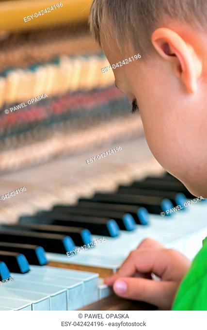 Little young caucasian boy playing on the piano outside train station