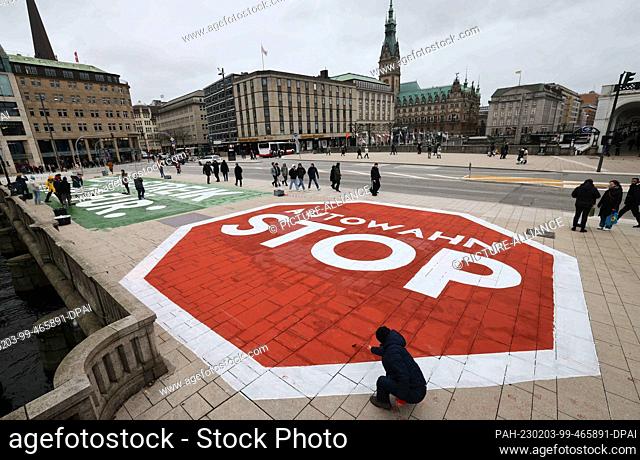 03 February 2023, Hamburg: Activists of the climate movement Fridays for Future paint a protest text on the Jungfernstieg near the city hall